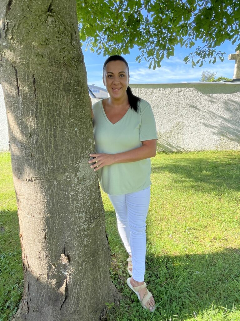 Silke Lindorfer steht unter einem Baum im Sommer mit weißer Kleidung.